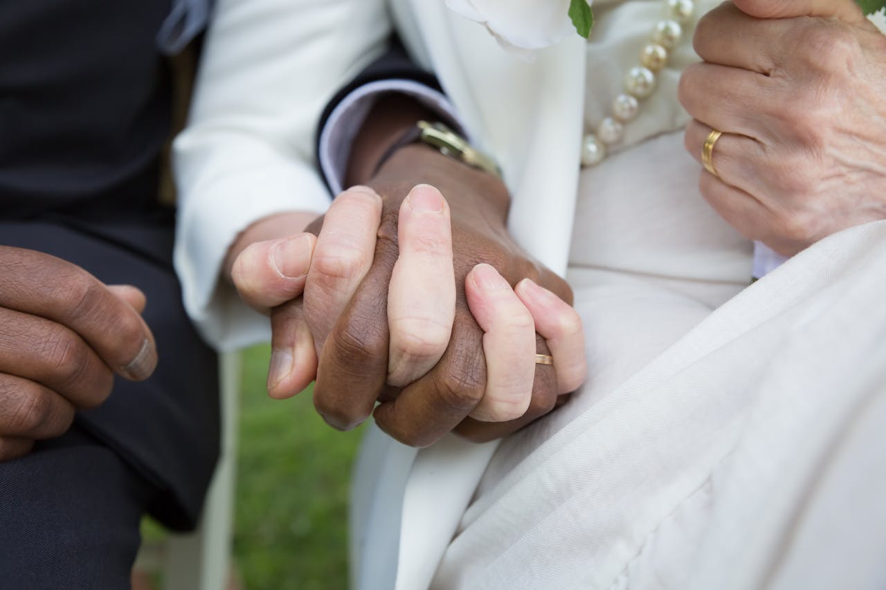 Close-up of an interracial couple holding hands at a wedding in Portugal.