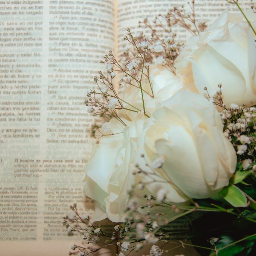 An open Bible with a beautiful bouquet of white roses and baby's breath.