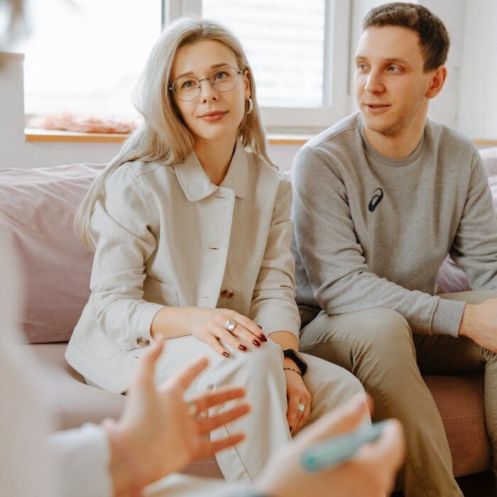 A couple engaged in a therapy session with a therapist indoors.